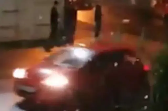 Youths on a street corner as a car goes past