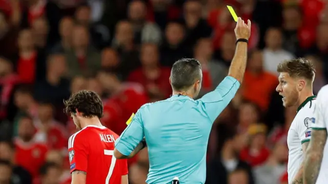 Joe Allen is shown a yellow card