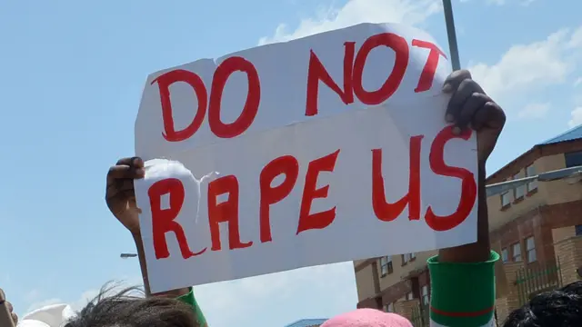 A protester in South Africa holding up a sign reading: "Do not rape us".