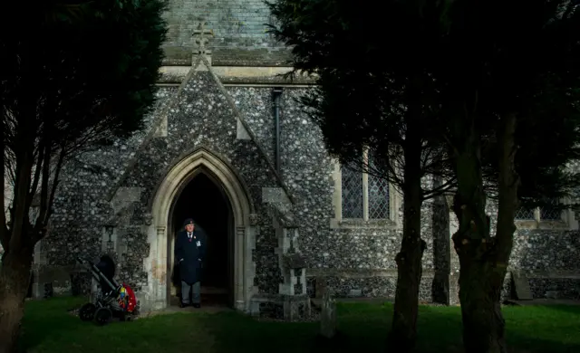 An armed forces veteran wears a poppy as he stands in the church porch