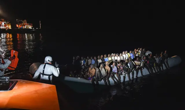 Migrants and refugees seated on a rubber boat receive instructions during a rescue operation by the crew of the Topaz Responder, a rescue ship run by Maltese NGO 'Moas' and the Italian Red Cross, on November 4, 2016 off the coast of Libya.