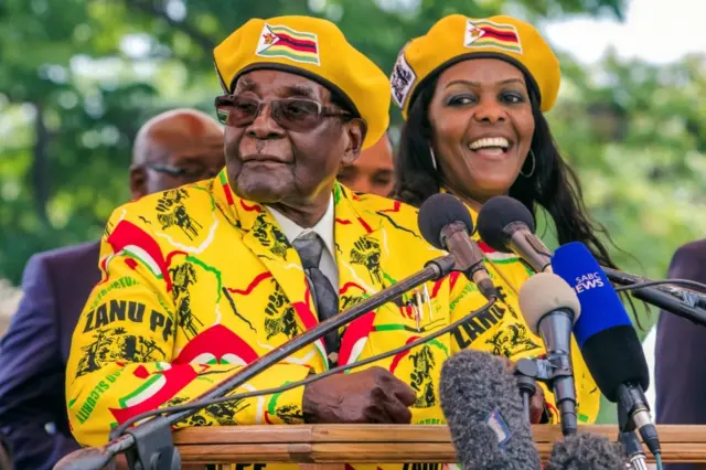 Robert Mugabe (L) addressing party members and supporters gathered at his party headquarters to show support to Grace Mugabe (R)