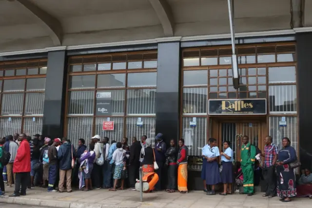 Members of the public wait outside a bank to withdraw cash in Harare, Zimbabwe, 15 November 2017.