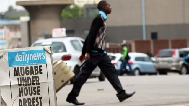 A man walking near a newspaper sign reading "Mugabe Under House Arrest" in Harare, Zimbabwe - 16 November 2017