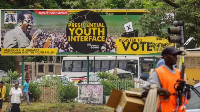 People walk past a banner of Zimbabwean President Robert Mugabe outside the Zanu-PF headquarters in the Zimbabwean capital Harare - 16 November 2017