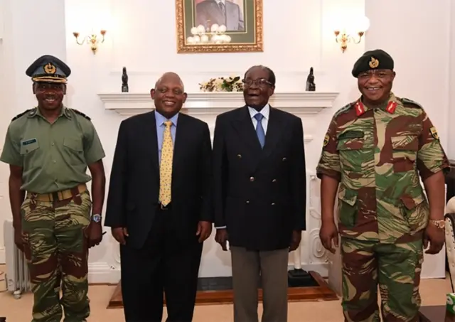 This screengrab from Zimbabwe Broadcasting Corporation (ZBC) taken on November 16, 2017, shows Zimbabwe President Robert Mugabe (2R) as he poses alongside Zimbabwe Defence Forces Commander General Constantino Chiwenga (R) and South African envoys at State House in Harare