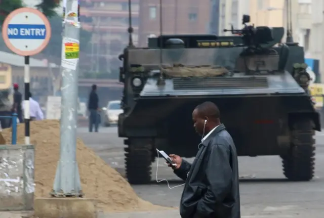 A man uses a mobile phone as he crosses the street in Harare, Zimbabwe November 17, 2017.