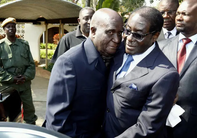 Former Zambia's first President Kenneth Kaunda (L) embraces Zimbabwean President Robert Mugabe