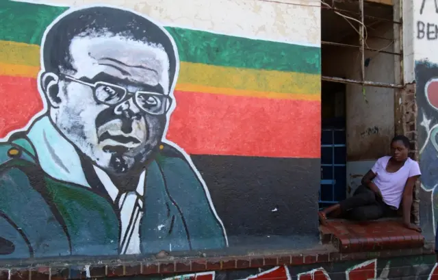 A woman looks out next to a mural of Zimbabwean President Robert Mugabe in Mbare, a impoverished township, in Harare, Zimbabwe, November 21, 2017