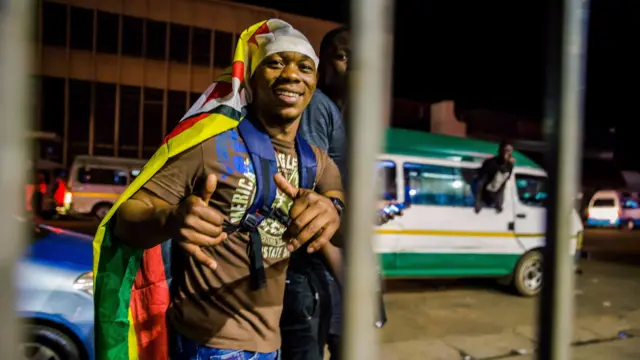 A man wearing the national flag celebrates in the streets after the resignation of Zimbabwe"s president Robert Mugabe on November 21, 2017 in Harare