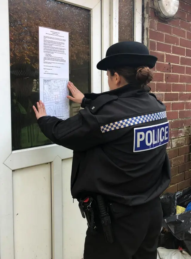 Police officer places sign on house door