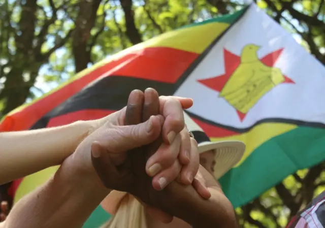 Locals hold hands as they attend a prayer meeting called to force Zimbabwean President Robert Mugabe to resign outside Parliament Building in Harare, Zimbabwe, November 20, 2017.