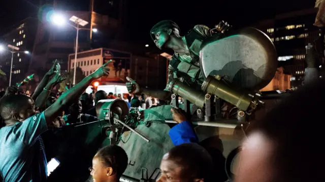 A Zimbabwean soldier sitting in tank gestures as people greet and celebrate after the resignation of President Mugabe, on November 21, 2017.