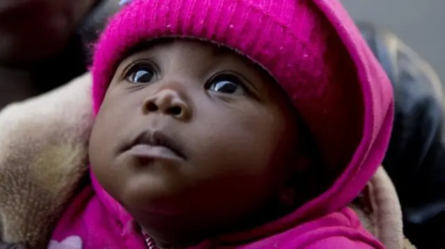 A baby girl looks up at her parent