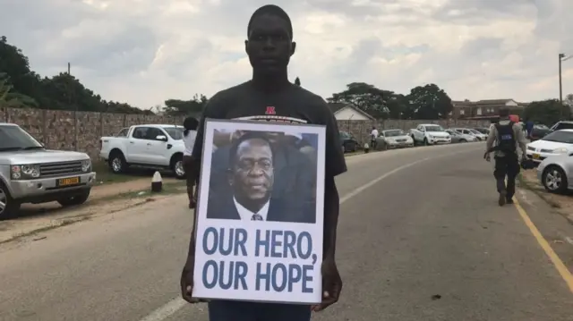 A man holding a placard reading: "Our hero, our hope"