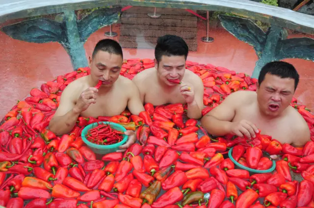 Men sitting in a bath of chillis