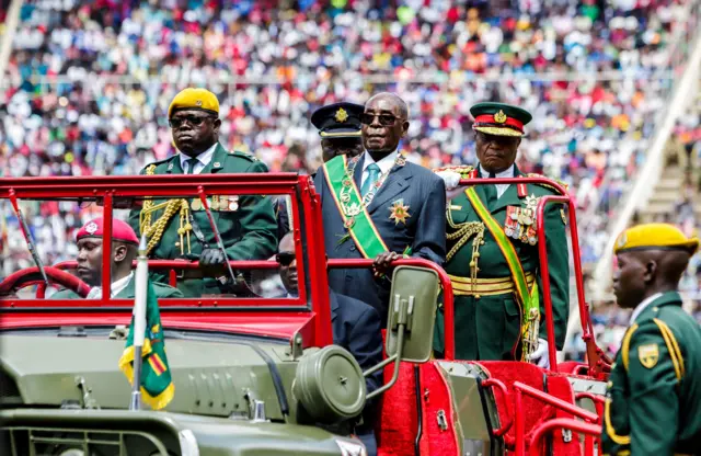 Robert Mugabe inspecting a guard of honour in a truck