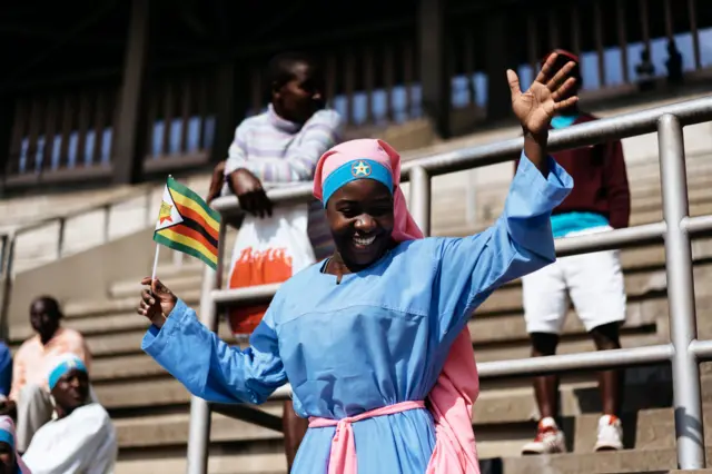 A member of the Christian Church Jowani Masowe Vadzidzi Vajesu holds a Zimbabwean flag at the National Sport Stadium in Harare,