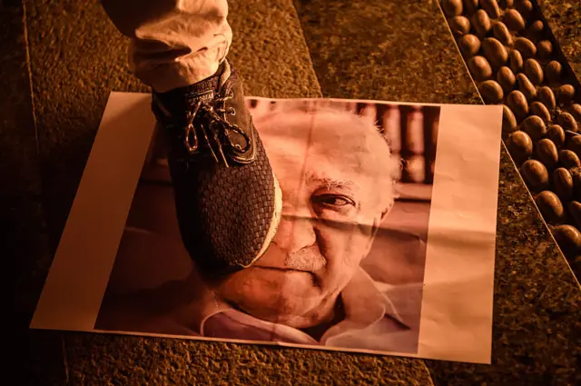 Pro-Erdogan supporter walks on a poster picturing US-based preacher Fethullah Gulen during a rally at Taksim square in Istanbul on July 18, 2016 following the military failed coup attempt of July 15