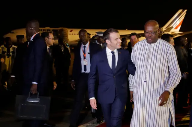 French President Emmanuel Macron (2nd-R) is welcomed by Burkina Faso"s President Roch Marc Christian Kabore (R) at Ouagadougou airport, Burkina Faso November 27, 2017.