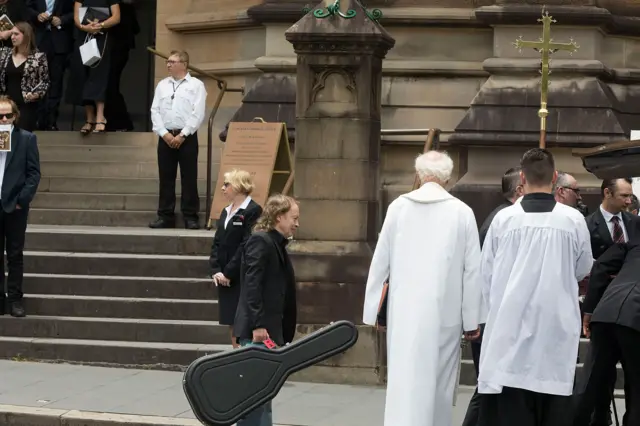 Angus Young carries his brother's guitar case