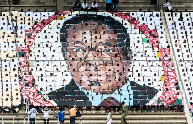 School children hold an image of Zimbabwe's President Robert Mugabe during the country's 37th Independence Day celebrations at the National Sports Stadium in Harare April 18, 2017