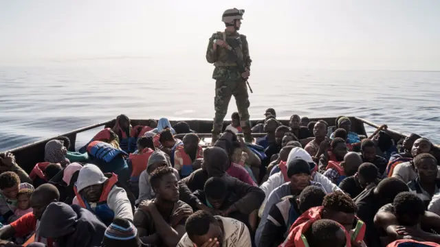 A Libyan coast guardsman stands on a boat during the rescue of 147 illegal immigrants attempting to reach Europe off the coastal town of Zawiyah,  27 June 2017