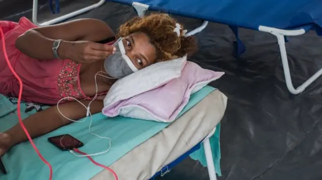 A woman lays on a hospital bed in Madagascar