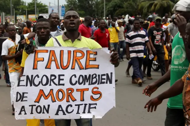 A man holds up a sign, which reads: "Faure, still how many death by you", during an opposition protest calling for the immediate resignation of President Faure Gnassingbe in Lome, Togo, September 2017