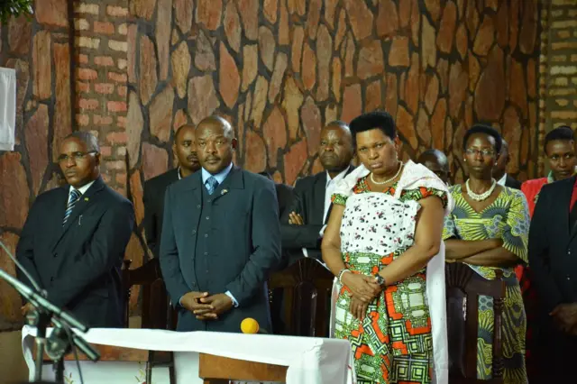 Denise Nkurunziza stands in church with a baby strapped to her back