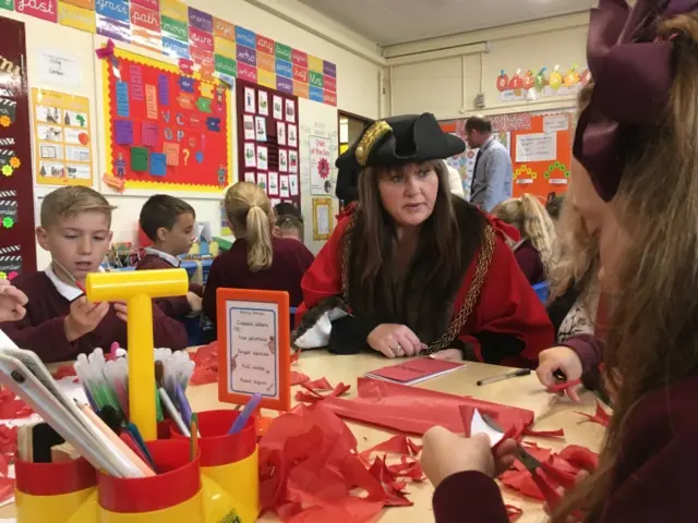 The Mayor sits with youngsters while they cut out paper poppy petals