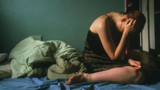 Depressed adolescent girl holds her head in her hands.