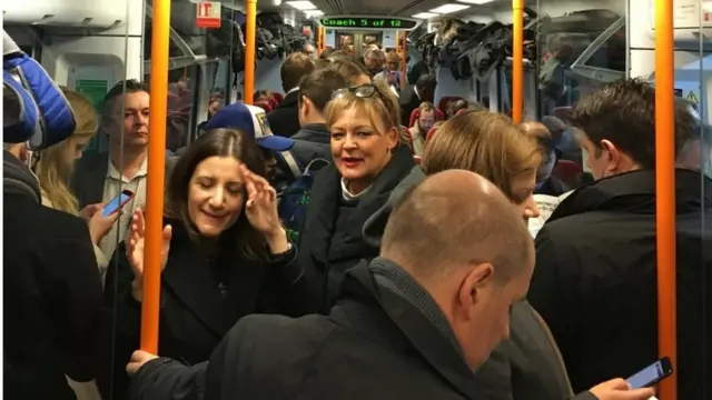 Commuters ride a crowded South Western Railway train