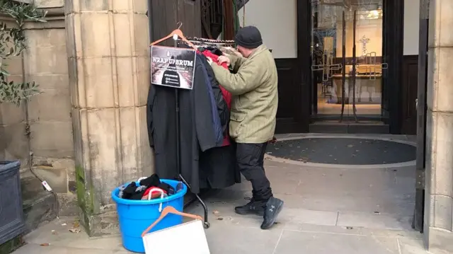 A man going through coats on a rail