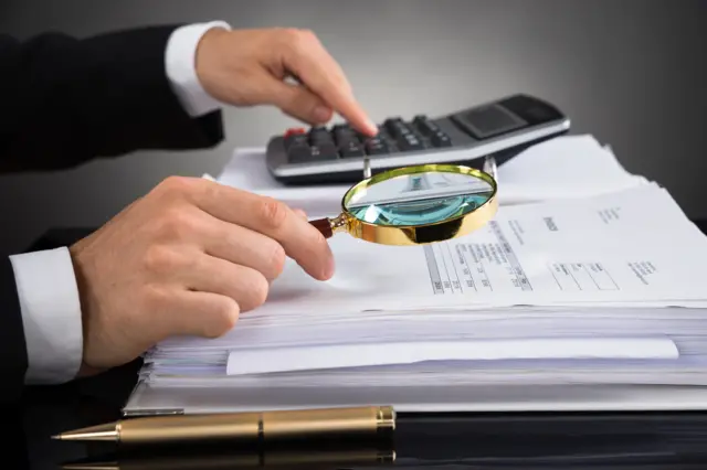 A man examines documents with a magnifying glass