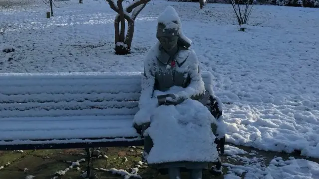 Sculpture on bench covered in snow