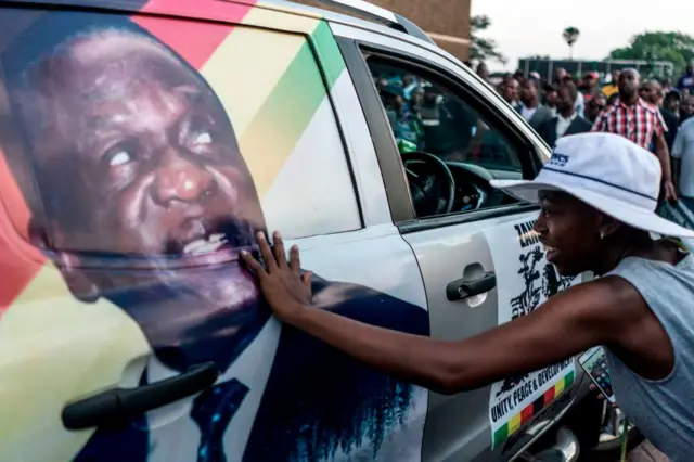 A supporter of Emmerson Dambudzo Mnangagwa touches an image of the politician glued on a SUV at the ZANU-PF headquarter in Harare, on November 22, 2017.