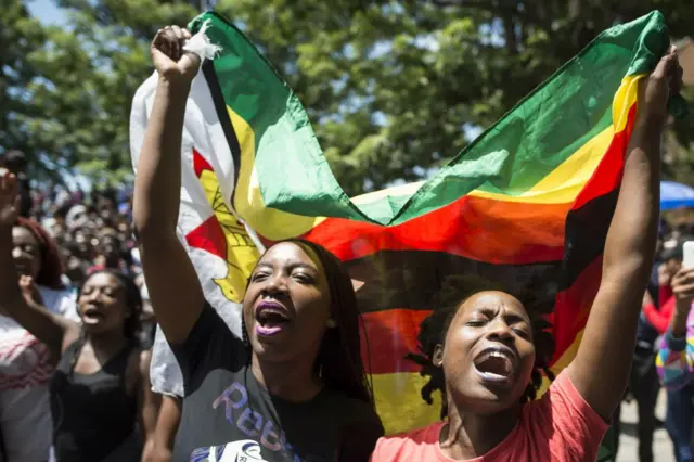 Women holding a flag of Zimbabwe take part in a demonstration of University of Zimbabwe's students, on November 20, 2017 in Harare, to demand the withdrawal of Grace Mugabe's doctorate and refused to sit their exams as pressure builds on Zimbabwe's President Robert Mugabe to resign. Zimbabwe's President faced the threat of impeachment by his own party on November 20, 2017, after his shock insistence he still holds power in Zimbabwe despite a military takeover and a noon deadline to end his 37-year autocratic rule.