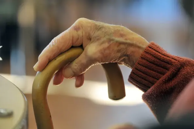 anonymous shot of elderly person's hand and walking stick