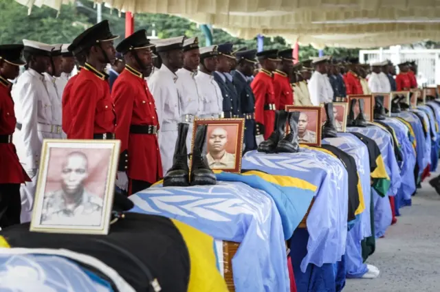 Soldiers of Tanzania People"s Defence Force (TPDF) stand beside the coffins of Tanzanian peacekeeperes who were killed by by suspected Ugandan rebels, at the headquarters of Tanzania People"s Defence Force in Dar es Salaam on December 14, 2017.