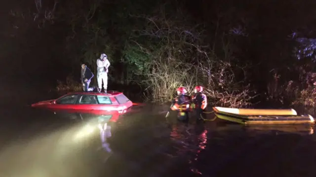 Pair on top of a car being rescued