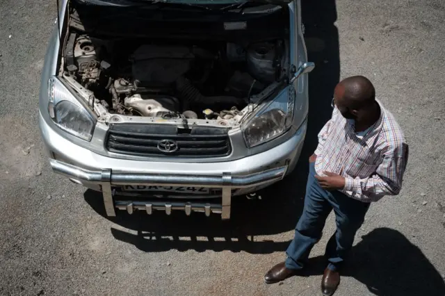 A manlooks under a car bonnet in Nairobi in 2017