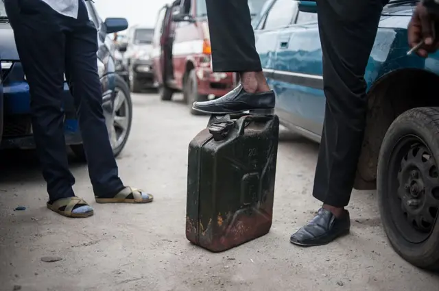 A man stand with his foot on top of his jerrican waiting to buy some fuel in Lagos on April 6, 2016.