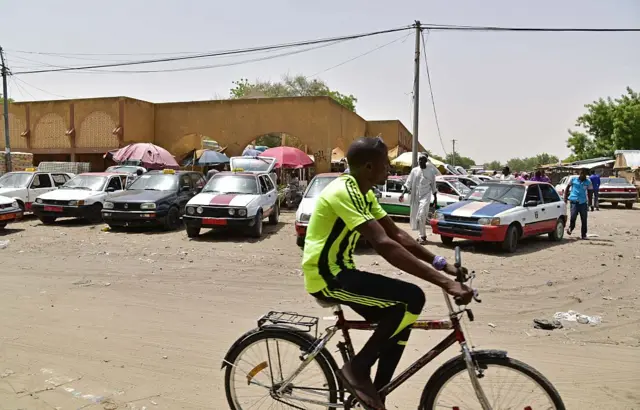 A man rides his bike man riding his bicyle next to taxis parked outside the central market in Diffa, southeast of Niger. Residents of Diffa, located near the Lake Chad and the border with Nigeria, live under the constant threat of attacks by the Islamic group Boko Haram.