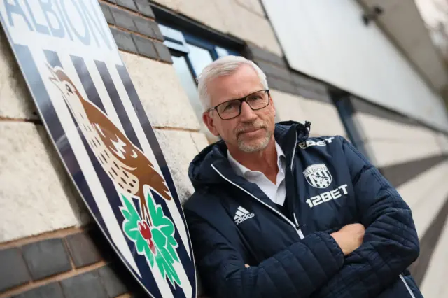 Alan Pardew poses next to a West Brom club crest