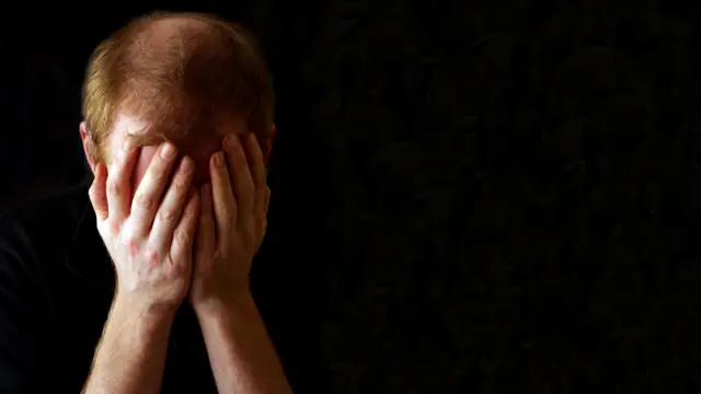 A man holding his head in his hands, as if depressed