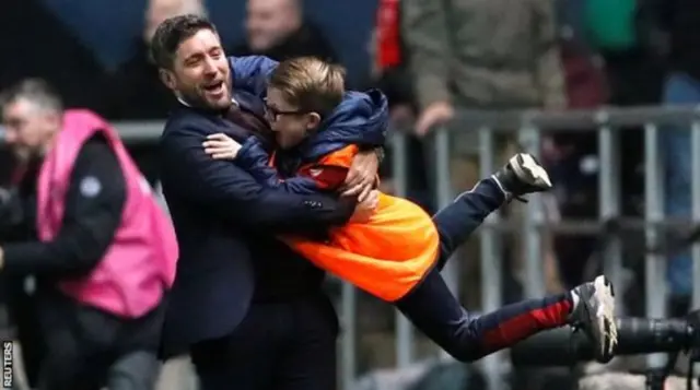 Lee Johnson swings a ball boy around in celebration