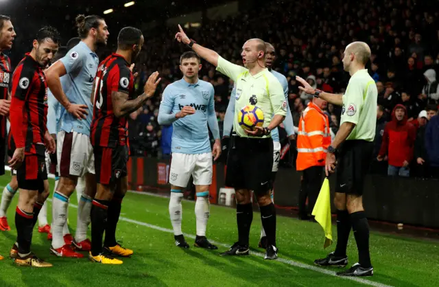 Players surround referee Robert Madley