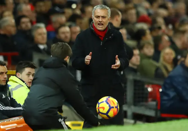 A ball boy passes the ball to Jose Mourinho