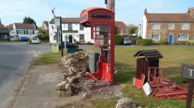 Smashed red phone box